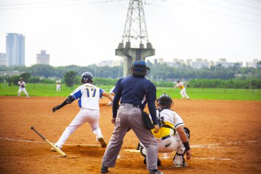 Nehir kenarındaki beyzbol kortu oyuncuları beysbol oynuyorlar.