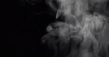 Siyah arkaplanın önündeki beyaz duman yavaşça yükseliyor.