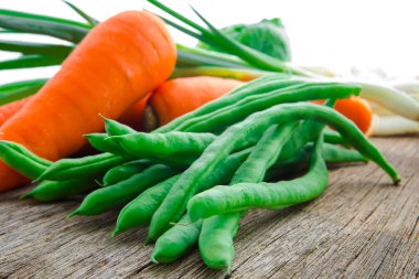 Ahşap masa üstünde havuçlu taze yeşil sebzeler.