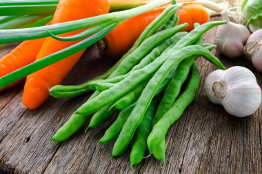 Ahşap masa üstünde havuçlu taze yeşil sebzeler.