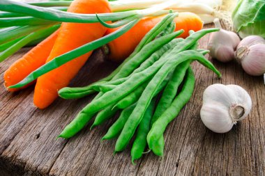 Ahşap masa üstünde havuçlu taze yeşil sebzeler.