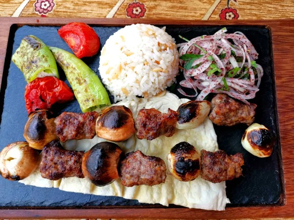 Meat skewers with rice on a black board background