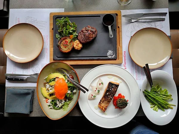 Delicious medium rare grilled steak and salmon on wooden board
