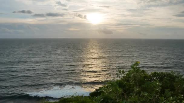 バリ島 インドネシア 1月22 2018 インド洋の波が美しいリラックスした夕日とバリの前景にある緑の植物で海岸を粉砕します 4Kワイドショット — ストック動画