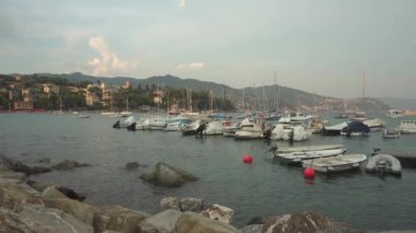 RAPALLO, LIGURIA, ITALY - 22 AĞUSTOS 2018: Yaz günbatımında Rapallo 'da kayalık kıyısı yakınlarındaki küçük tekneler. 4K, geniş açı, el bilgisayarı