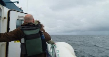 GALway BAY, IRELAND - 13 Ağustos 2023: Atlantik Okyanusu 'nda rüzgarlı bir havada feribotta orta yaşlı bir çift Galway' den Inishmore, İrlanda 'ya giden yolda - 4K, Editoryal, El bilgisayarı, Orta uzunluktaki