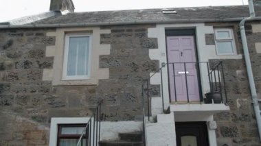 BURNTISLAND, FIFE, İngiltere - 13 Haziran 2024: Burntisland, Fife 'da küçük bir balkon ve pembe kapısı olan büyüleyici bir taş kulübe.