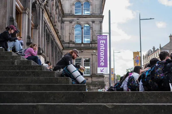 stock image EDINBURGH - JULY 28, 2024: Groups of people gather and unwind on the steps of the National Museum in Edinburgh, enjoying the atmosphere on a sunny day.