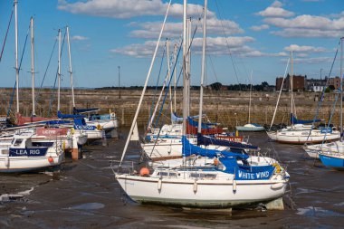 EDINBURGH - 28 Temmuz 2024: Birden fazla yelkenli, alçak gelgit sırasında Balıkçı Yayı 'nın çamurlu düzlüklerinde, berrak mavi bir gökyüzü altında, tüylü bulutlarla benekli.