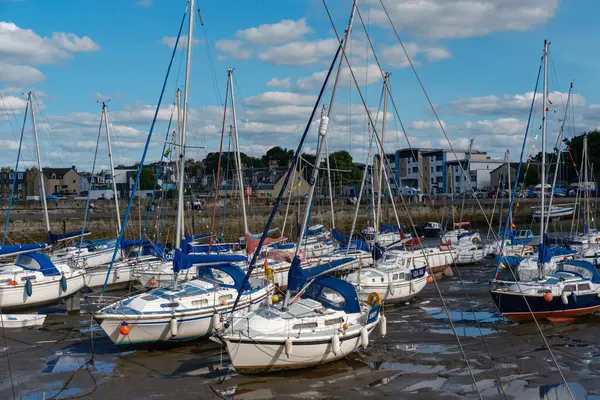 stock image EDINBURGH - JULY 28, 2024: Sailboats are anchored and tilted in the mud at low tide along Fisherrow Harbour marina, with buildings visible in the background under a bright blue sky.