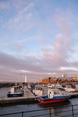 Newhaven Limanı 'nda hafif dalgalar dalgalanır. Tekneler yavaşça sallanır. Gün batımına karşı siluet olur..