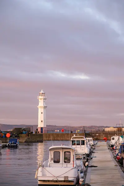 Newhaven Limanı, Edinburgh 'daki deniz feneri iskelede dinlenen tekneler gibi dimdik ayakta duruyor, batan güneşin ılık renklerinde banyo yapıyorlar..