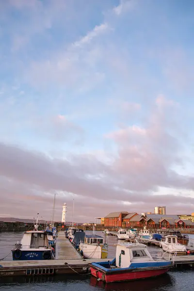 stock image At sunset, boats are docked at Newhaven Harbour in Edinburgh while the lighthouse stands tall against the colorful sky, creating a picturesque evening atmosphere.