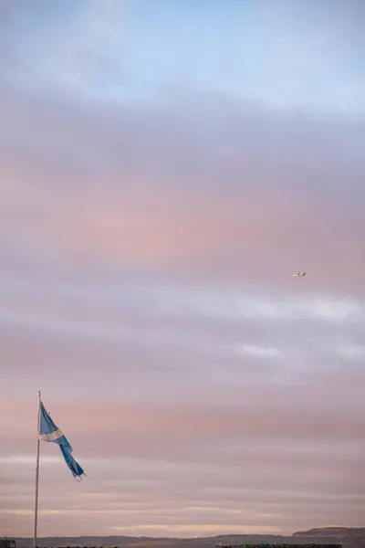 Canlı bir günbatımı Newhaven Limanı 'nın üzerindeki gökyüzünü İskoç bayrağı ve gökyüzünde bir uçak ile resmediyor ve barışçıl bir atmosfer yaratıyor..