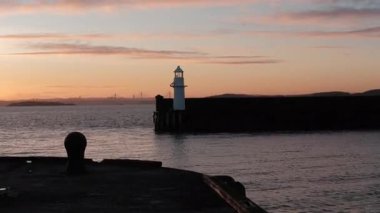BURNTISLAND, FIFE, SCOTLAND, İngiltere - 4 HAZİRAN 2025: Sakin suların üzerine altın renkler dökerek Burntisland Batı İskelesi Deniz fenerinin geniş açılı, sakin bir atmosferini oluşturan nefes kesici günbatımı.