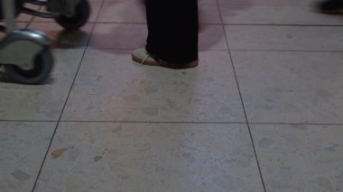 EDINBURGH, SCOTLAND, İngiltere - 21 Ekim 2024: Yolcular Edinburgh Havalimanı terminalinden geçerken bagaj arabalarını, ayakları ve zemin fayanslarını kapatıyorlar.