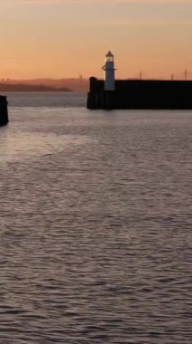 BURNTISLAND, FIFE, SCOTLAND, İngiltere - 4 HAZİRAN 2025: Sersemletici günbatımı gökyüzünü aydınlatıyor, sakin sular Burntisland limanı yakınlarındaki renkleri yansıtıyor, Batı İskelesi Deniz feneri ve Dördüncü Köprü manzarası