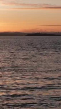 BURNTISLAND, FIFE, SCOTLAND, İngiltere - 4 HAZİRAN 2025: Gün batımının son ışınları Firth of Forth ve Burntisland Batı İskelesi Deniz fenerinin sakin suları üzerinde canlı renkler sergiliyor,.