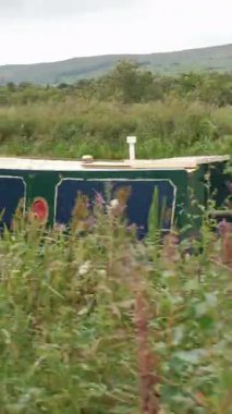 AUCHINSTARRY, NORTH LANARKSHIRE, SCOTLAND, UK - 18 AĞUSTOS 2024: Bulutlu bir yaz gününde Auchinstarry Marina 'da yemyeşil bir tekne boyunca yürü.