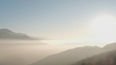 TADAPANI, NEPAL - 11 Ocak 2025 Sabah güneşi Annapurna bölgesinin görkemli tepelerini vurguluyor, sisli gün doğumu, gösterişli doğa güzelliği ve dinginliği, rahatlama arka planı.