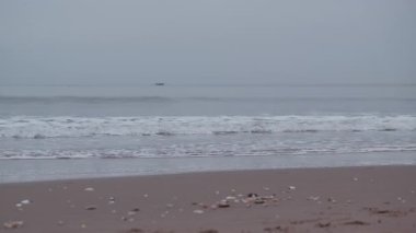 Bulutlu güneşin doğuşunu seyret Portobello Sahili üzerinde yumuşak bir parıltı yayıyor, kıyıya vuran sakin dalgaları vurguluyor..