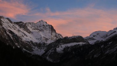 Sunlit pink clouds over Mount Arpelistock in winter.