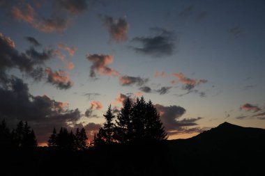 Renkli bulutlar, ağaç hatları ve Blattipass 'tan görünen bir zirve..