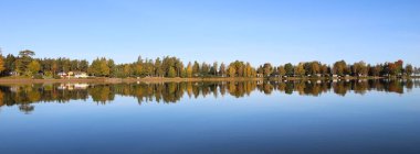 Sakin bir sonbahar günü, Vanern Gölü 'nde yansıyan renkli ağaçlar, İsveç.