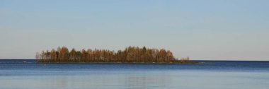 Autumn scene at Lake Vanern, Sweden. Tiny island covered by colorful forest. clipart