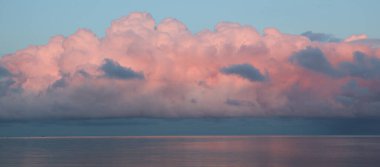 İsveç 'te, gün batımında Vanern Gölü üzerinde pembe kümülüs bulutu..