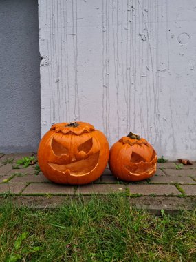 Köşede oyulmuş iki balkabağı kafası duruyor. Jack O 'Lantern oyulmuş bir fenerdir. Şeytani asık surat. Sonbahar şaka mı şeker mi festivalini kutluyoruz. Turuncu balkabağı.