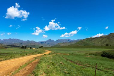 Yeşil tarlalardan geçip Drakensberg Dağı 'na giden çakıl yolu Güney Afrika