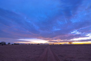 Güneş battıktan sonra Namibya çölünde mavi, pembe ve sarı bulutlar