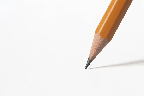 Tahta bir kalemin ucu beyaz bir kağıda gölge düşürüyor. Beyaz arkaplan