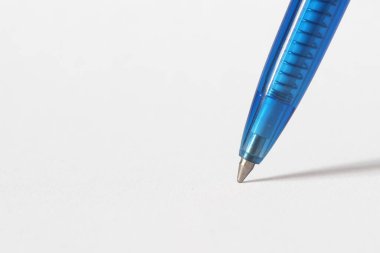 Beyaz kağıda gölge düşüren mavi tükenmez kalemin ucu.