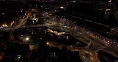Amsterdam şehir merkezinin gece boyunca gökyüzü görüntüsü. Amsterdam Centraal, Lj, Prins Hendrikkade, toplu taşıma, gece trafiği. Parlak ışıklar kentsel