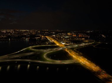 Gece A10 karayolu trafiği. Hollanda 'nın Amsterdam Ijburg şehrinde yol üzerindeki hareketli dinamik trafik ışığı altındaki karayolu altyapısı. Hava aracı gece fotoğrafçılığı.