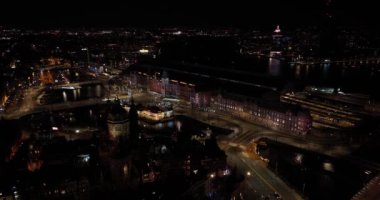 Amsterdam şehir merkezinin gece boyunca gökyüzü görüntüsü. Amsterdam Centraal, Lj, Prins Hendrikkade, toplu taşıma, gece trafiği. Parlak ışıklar kentsel