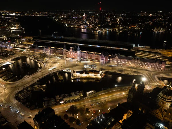 Amsterdam city center skyline by night aerial drone overhead view. Amsterdam Centraal, Ij, Prins Hendrikkade, public transport, traffic at night. Bright lights urban