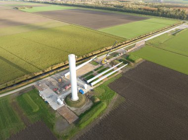 Hollanda 'da yeşil enerji üreten bir rüzgar türbininin inşaat sahası. Sürdürülebilir enerji geçişi yapılıyor. Yel değirmeninin vinçlerle yapılmış hava aracı görüntüsü. Yeşil elektrik enerjisi
