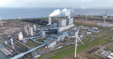 Electricty generation facility. Aerial drone overhead view. Smokestack, wind turbine, sea, industrial building exterior. Smoke factory.