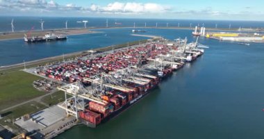 Rotterdam, 19th of January 2023, The Netherlands.Drone footage of a container terminal, large cranes moving containers on off of cargo ships, rows of stacked containers, and trucks loading and