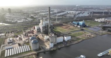 A birdseye view of a coal power plant in a large harbour, showcasing the industrial infrastructure and technology used to generate electricity in a unique setting. Overhead aerial