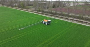 Çiftçi tarlayı traktörle ilaçlıyor. Hava aracı görüntüsü. Tarım manzarası.