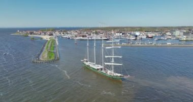 Limanın hareketli hareketlerini ele alalım. Büyük bir yelkenli gemi geliyor. Deniz taşımacılığının enerjisini ve heyecanını gözler önüne seriyor..