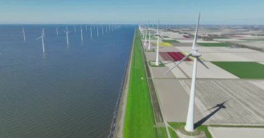 Güneşli bir baharda yeşil enerji üreten rüzgâr türbini parkının uzaktan kumandalı hava aracı videosu.