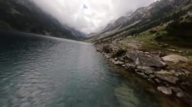 Bir dağ gölünün FPV hava aracı videosu. Karla kaplı zirveler. Fransa.