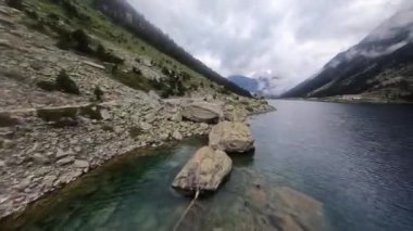Bir dağ gölünün FPV hava aracı videosu. Karla kaplı zirveler. Fransa.
