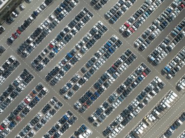 Büyük bir otoparkta tepeden aşağıya insansız hava aracı görüntüsü. Araç park etme.