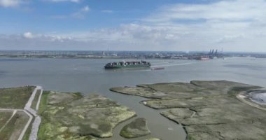 Antwerpen limanından ayrılıp Schelde nehrine giden büyük bir konteynır gemisinin hava aracı görüntüsü. Uluslararası kargo sevkiyatı. Antwerpen, Belçika.